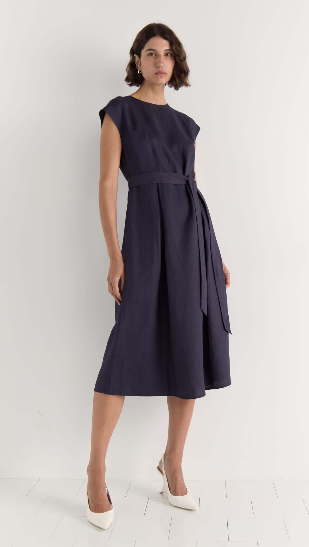 Rhea Midi Dress in deep navy, sleeveless style with self-tie belt, showcasing a midi length and elegant cap sleeves.