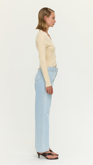 A model showcasing the Ornate Button Scallop Neck Cardi in Yellow paired with light blue jeans.