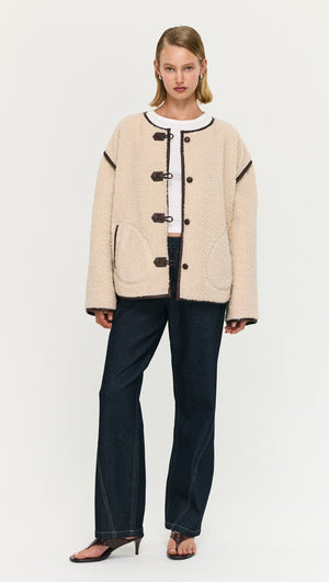 Brown Contrast Trim Duffle Coat in Teddy worn over a white top, styled with dark jeans and high-heeled sandals.