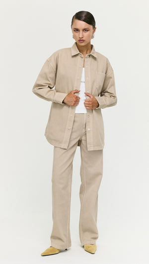 Model wearing a Stone Wash Relaxed Denim Shacket with matching beige pants and a white top.
