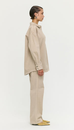 Woman wearing a Stone Wash Relaxed Denim Shacket styled with matching beige pants.