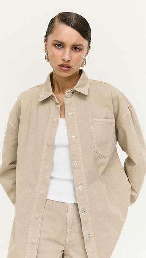 Stone Wash Relaxed Denim Shacket worn by a model, featuring a light beige color and relaxed fit, perfect for layering.