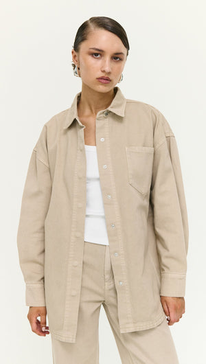 Model wearing a Stone Wash Relaxed Denim Shacket in a neutral color with a white top and beige pants.