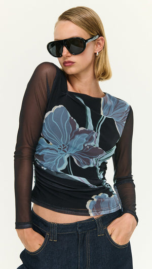 Model wearing a stylish Blue Floral Asymmetric Neck Mesh Top with sunglasses, showcasing a modern, chic outfit.