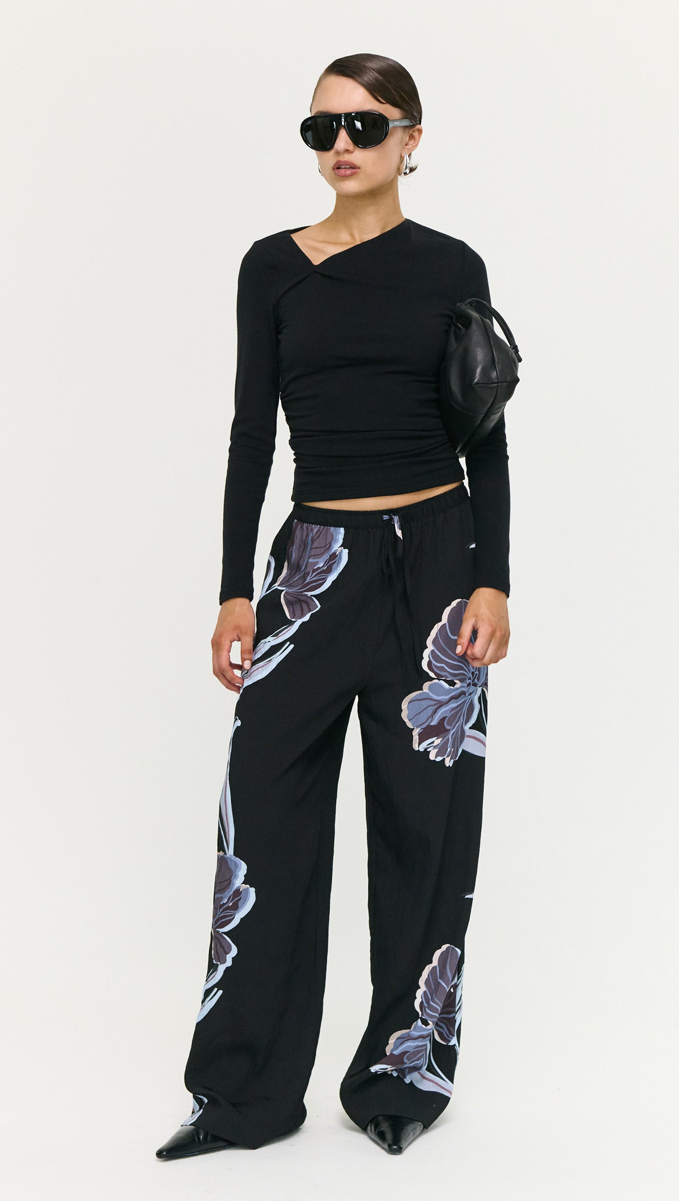 Model wearing Blue Floral Relaxed Drawstring Pant paired with a fitted black top and sunglasses, showcasing a chic off-duty look.