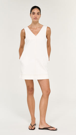 Model wearing a Cotton Denim Mini Shift Dress in White with pockets, minimalist design, ideal for casual outings.
