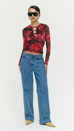 Model wearing Tie Waist Detail Mid Rise Jeans with a floral long sleeve top and sunglasses.