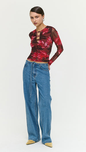 Model wearing Tie Waist Detail Mid Rise Jeans paired with a floral long-sleeve top and pointed-toe heels.