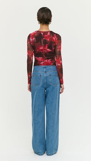 Back view of a model wearing a Pink Floral Print Mesh Bead Detail Top with wide-leg jeans.