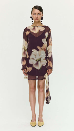 Model wearing a Sheer Floral Mini Dress with Tie Detail, featuring floral patterns and elegant long sleeves.