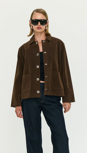 Model wearing a Chocolate Brown Faux Suede Barn Jacket with black sunglasses and jeans against a neutral background.