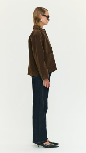 Model wearing a Chocolate Brown Faux Suede Barn Jacket paired with dark jeans, showcasing a stylish side profile.