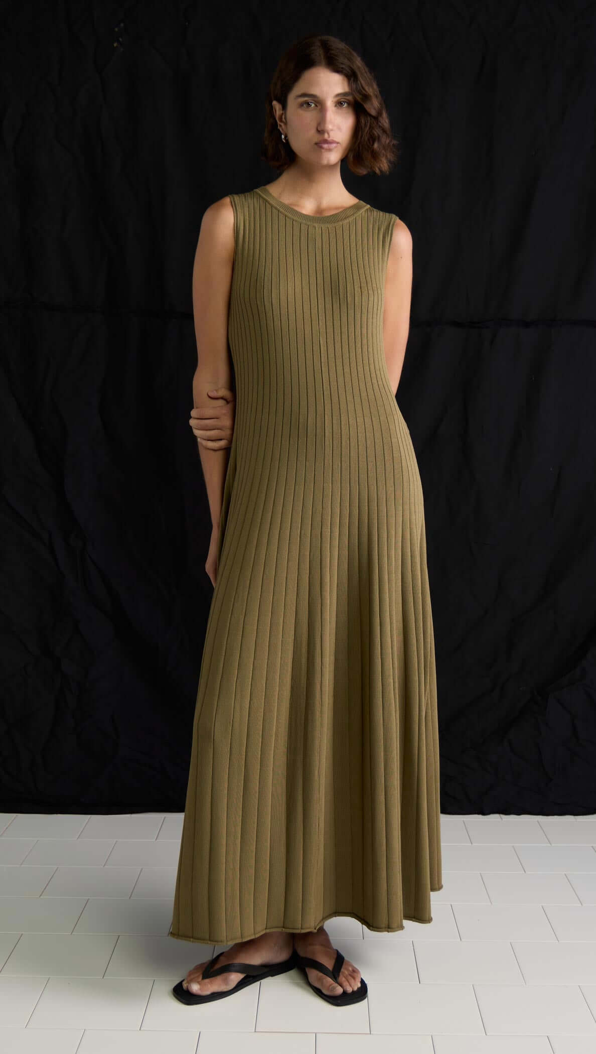 Olive-toned ribbed midi dress with sleeveless design and soft A-line silhouette, featuring keyhole back detail.