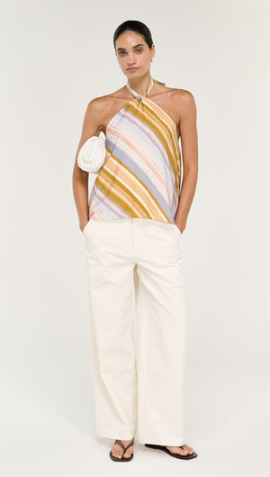 Model wearing a Pastel Stripe Twist Detail Halter Top with white wide-leg pants and a small handbag.
