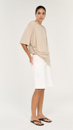 Asymmetric Draped Oversize Tee in Beige styled with white shorts and sandals, showcasing a casual chic look.