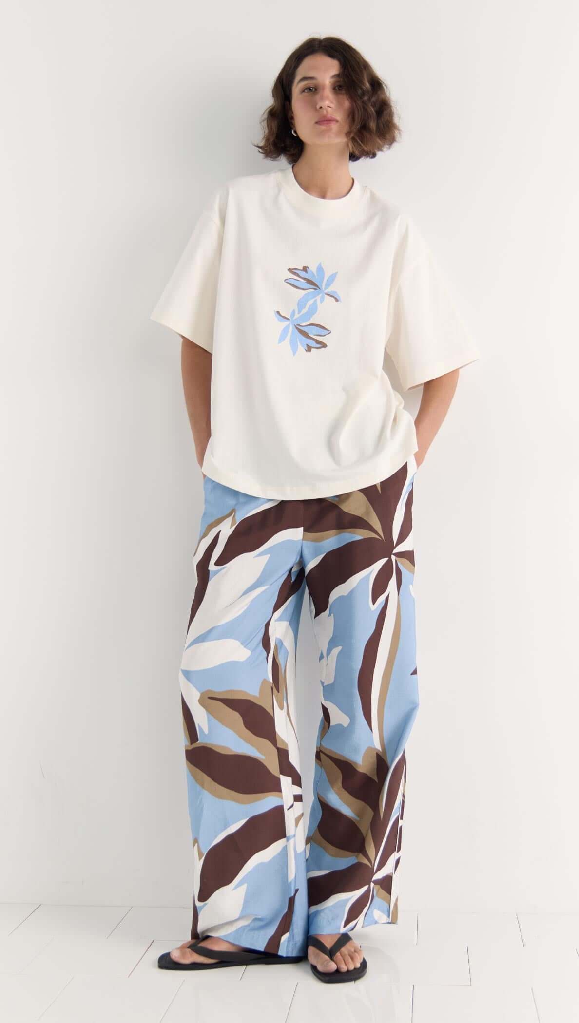 Model wearing Mae Graphic Tee with abstract floral print and matching floral pants in blue and brown tones.