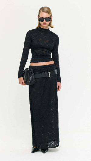 Model wearing a Black Sheer Lace Maxi Skirt paired with a fitted top and accessories, showcasing modern fashion style.