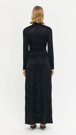 Back view of a model wearing a Black Sheer Lace Maxi Skirt, showcasing its elegant design and long silhouette.