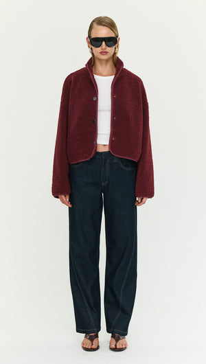 Model wearing a Burgundy High Neck Cropped Sherpa Jacket with black jeans and sunglasses.
