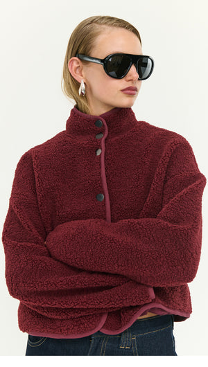 Woman wearing a Burgundy High Neck Cropped Sherpa Jacket with sunglasses, showcasing cozy style and modern design.