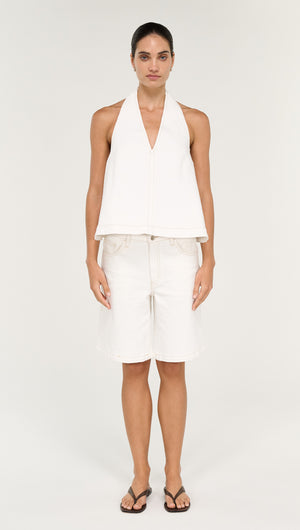 Model wearing Cotton Denim Mid Rise Jorts in White with a halter top and flip flops against a neutral background.