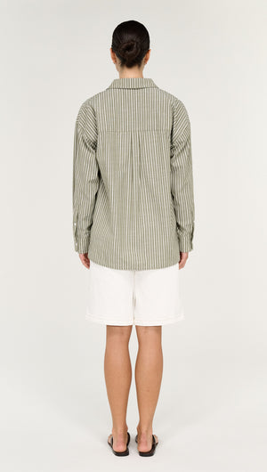 Model wearing a Khaki Stripe Cotton Oversized Shirt, showcasing the back view with white shorts and sandals.