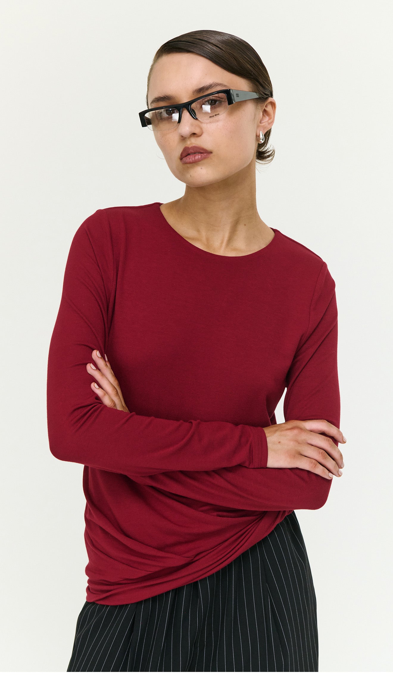 Model wearing a Long Sleeve Jersey Twist Top in Merlot paired with black striped wide-leg pants.