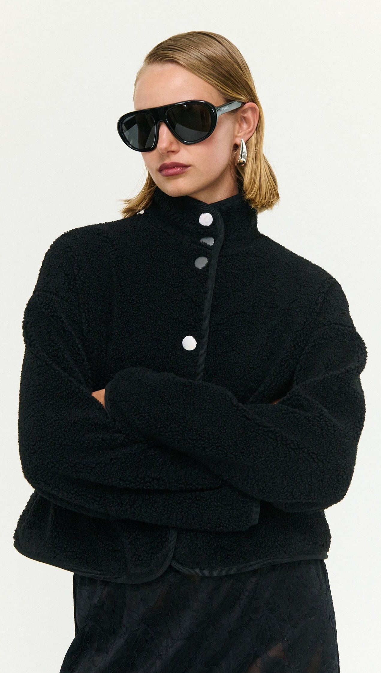Model wearing a Black High Neck Cropped Sherpa Jacket with stylish sunglasses, showcasing cozy winter fashion.