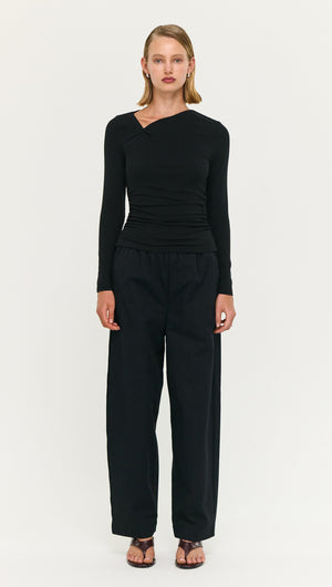 Model wearing a Black Soft Jersey Twist Neck Top with wide-leg black pants, showcasing a stylish and contemporary look.