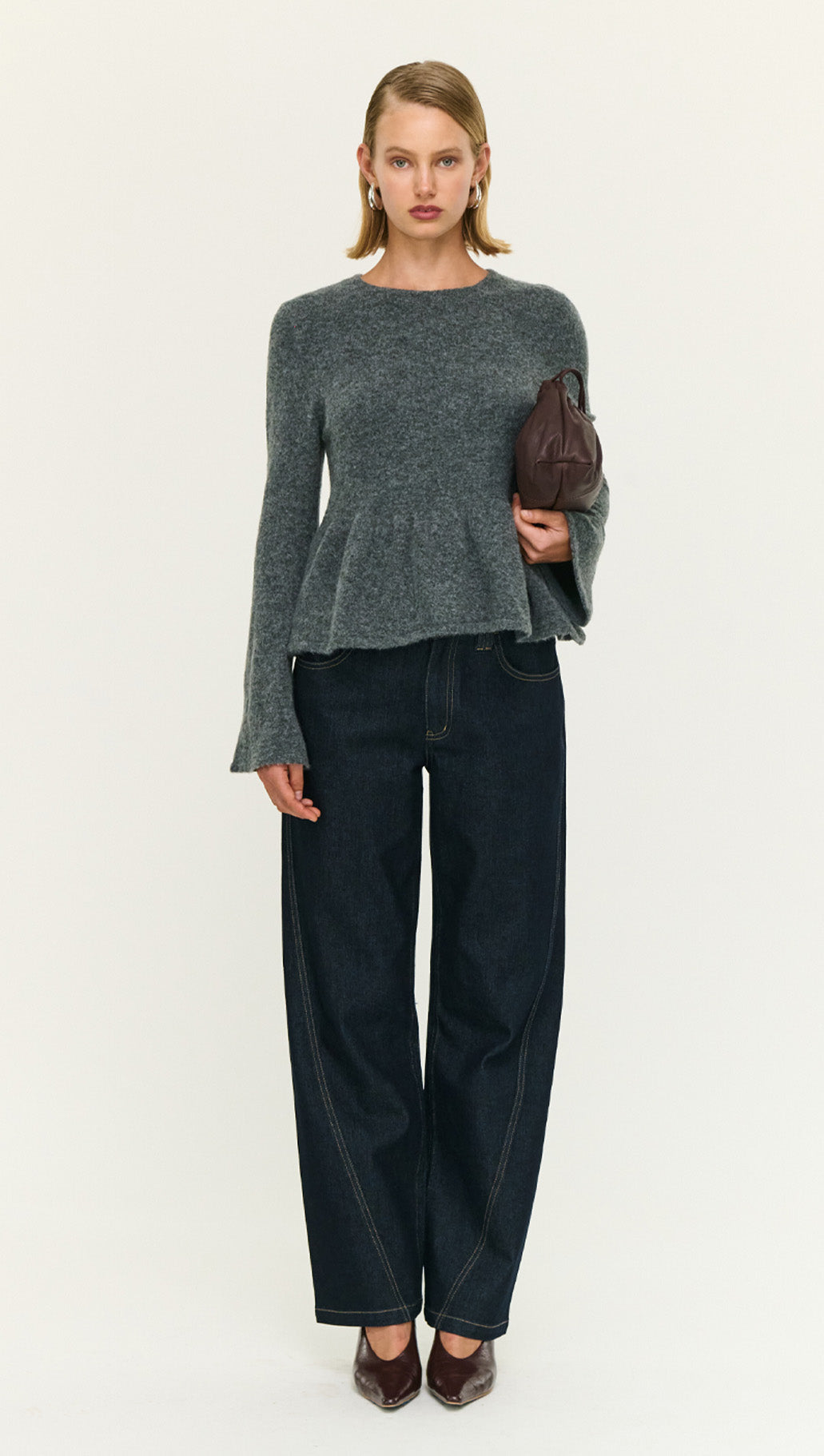 Model wearing a Soft Knit Peplum Top with Flute Sleeve paired with dark jeans.