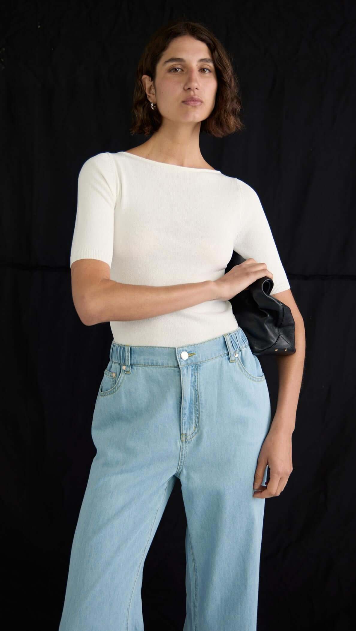 Model wearing Amelia Chambray Jeans with a relaxed wide-leg fit and light chambray blue color, paired with a fitted white top.