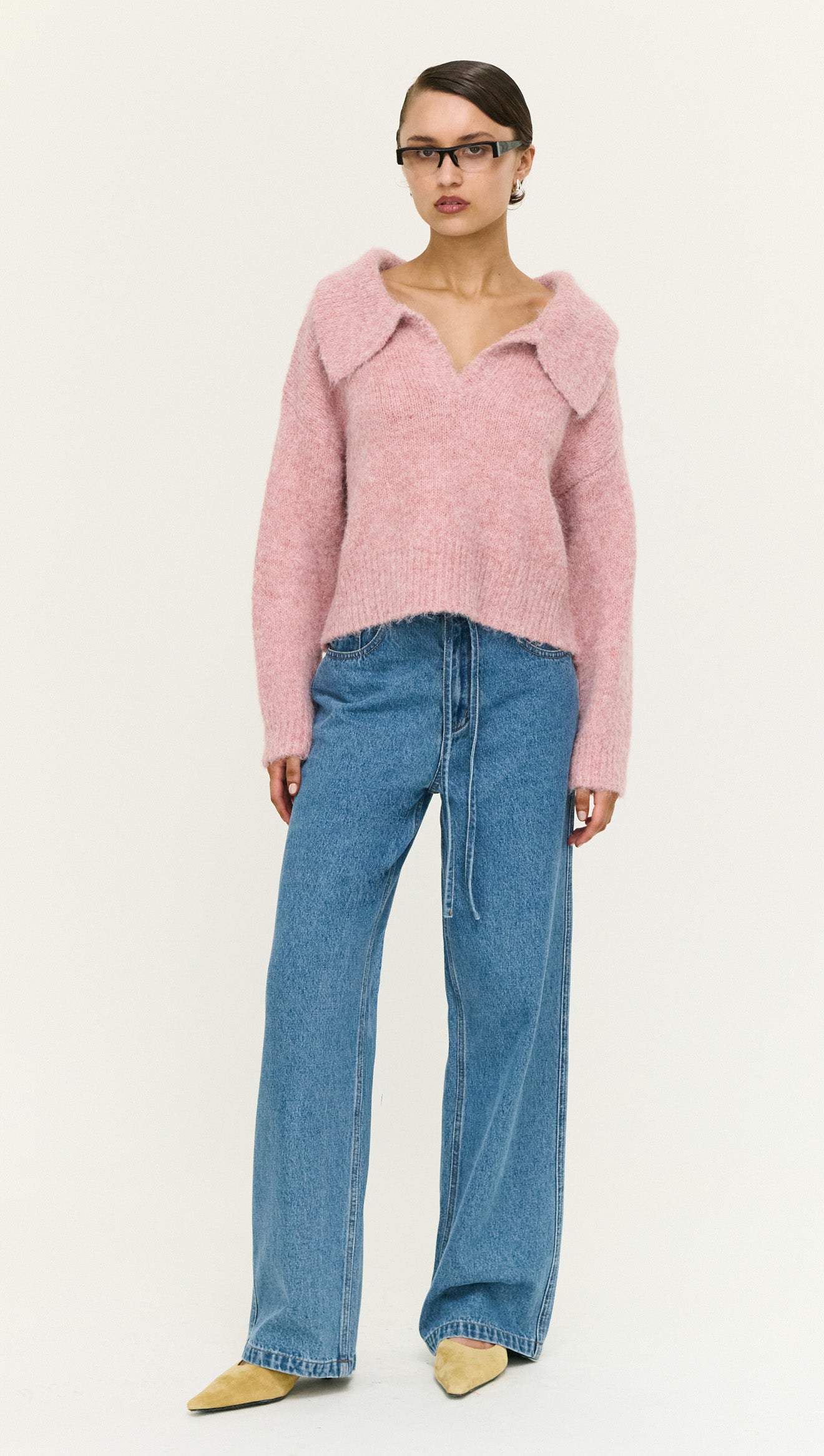 Model wearing a Dusky Pink Fluffy Knit Polo Jumper paired with high-waisted jeans and stylish heels, front view.