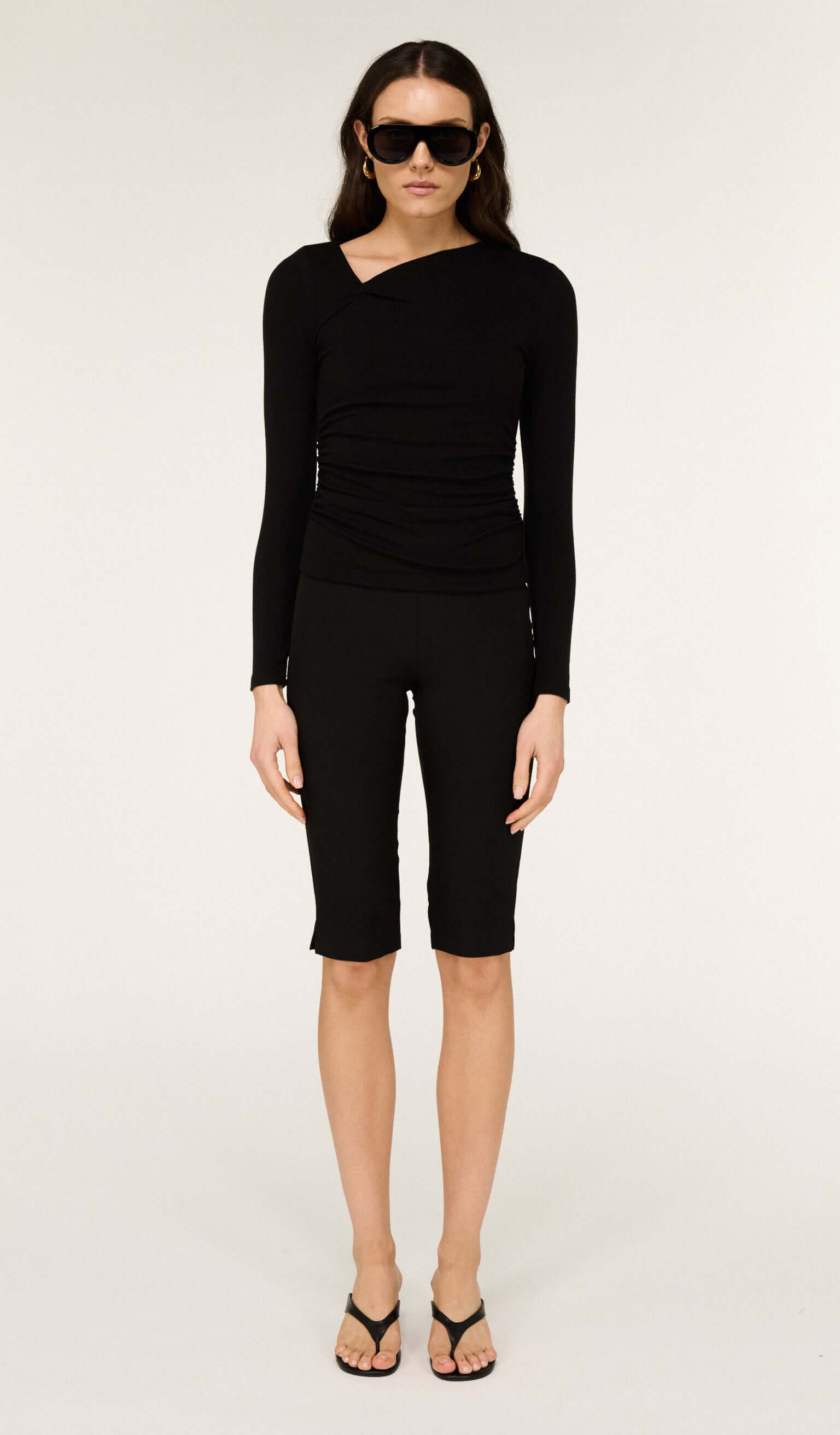 Model wearing Mid Rise Capri Pants in Black with a burgundy jacket and sunglasses, showcasing a trendy casual outfit.