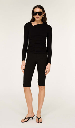 Model wearing Mid Rise Capri Pants in Black paired with a stylish long-sleeve top and sunglasses.