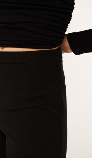 Close-up view of Mid Rise Capri Pants in Black showcasing the waistband and zipper detail.