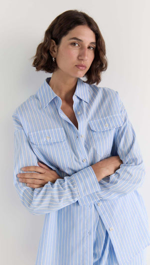 Model wearing the Ayra Pinstripe Shirt in blue stripe, featuring a relaxed fit, button-up front, and chest pockets.
