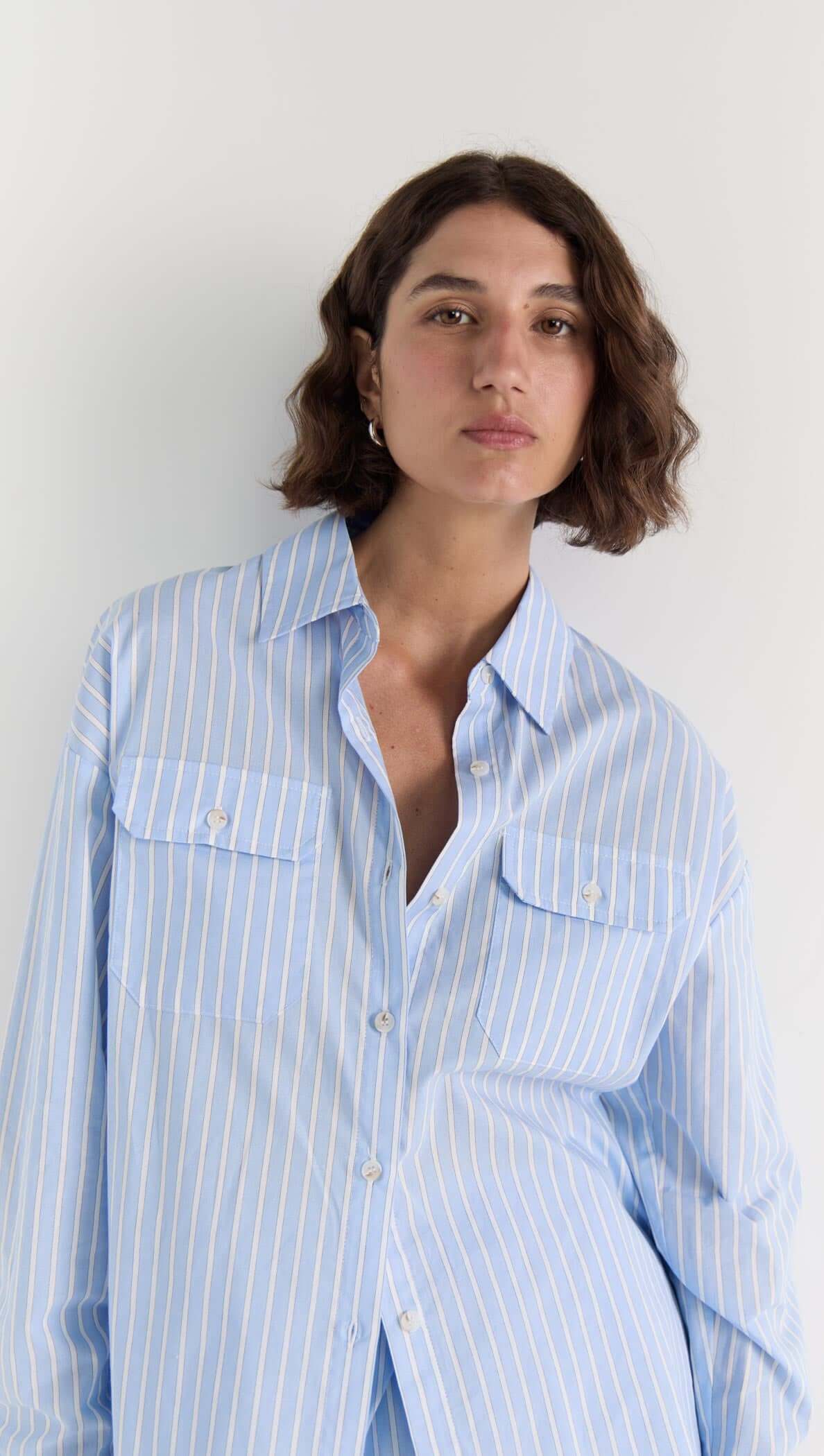 Model wearing the Ayra Pinstripe Shirt featuring a relaxed fit and blue stripe pattern with chest pockets.