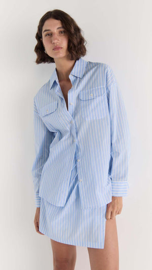 Model wearing Ayra Wrap Mini Skirt in blue stripe with matching shirt, portraying a chic summer look.