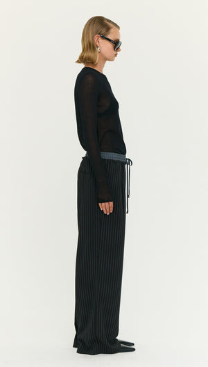 Model wearing Pinstripe Relaxed Drawstring Pants paired with a sheer black long-sleeve top and sunglasses.