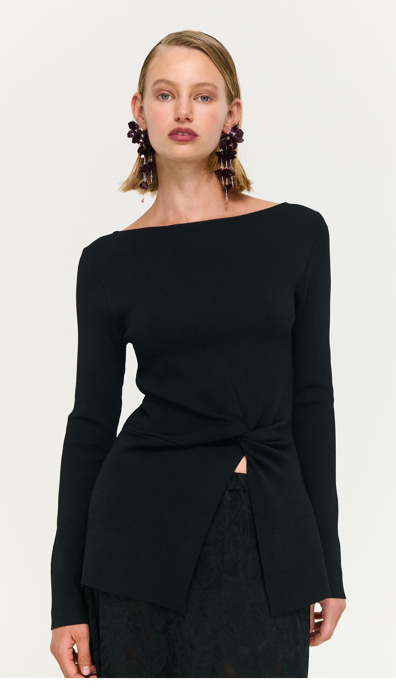 Model wearing a Black Boat Neck Twist Knit Top, showcasing a stylish twist knot detail and modern design.