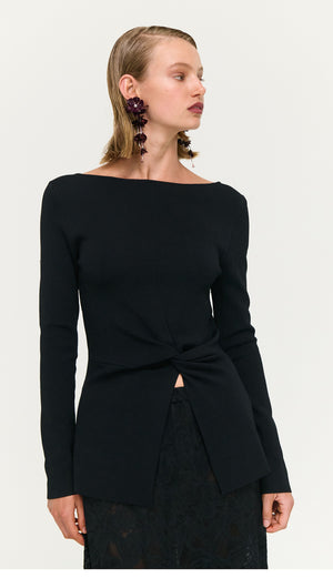 Model wearing a Black Boat Neck Twist Knit Top, styled with elegant earrings, showcasing a modern and chic look.