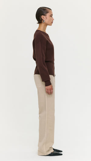 Model wearing a Brown Zip Detail Soft Crew Neck Knit with beige pants, shown in side profile on a neutral background.
