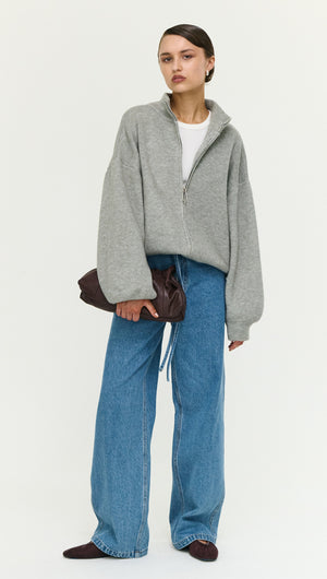 Model wearing a Soft Grey Oversized Zip Cardigan with wide-leg jeans and a brown clutch.