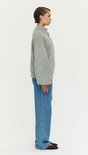 Model wearing a Soft Grey Oversized Zip Cardigan paired with high-waisted jeans, viewed from the side.