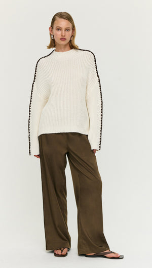 Model wearing a Blanket Stitch Detail High Neck Jumper with chic styling and loose-fitting pants.