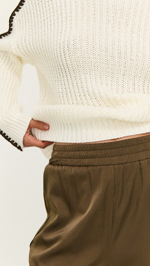 Close-up of a model wearing a Blanket Stitch Detail High Neck Jumper with stylish high-waisted trousers.
