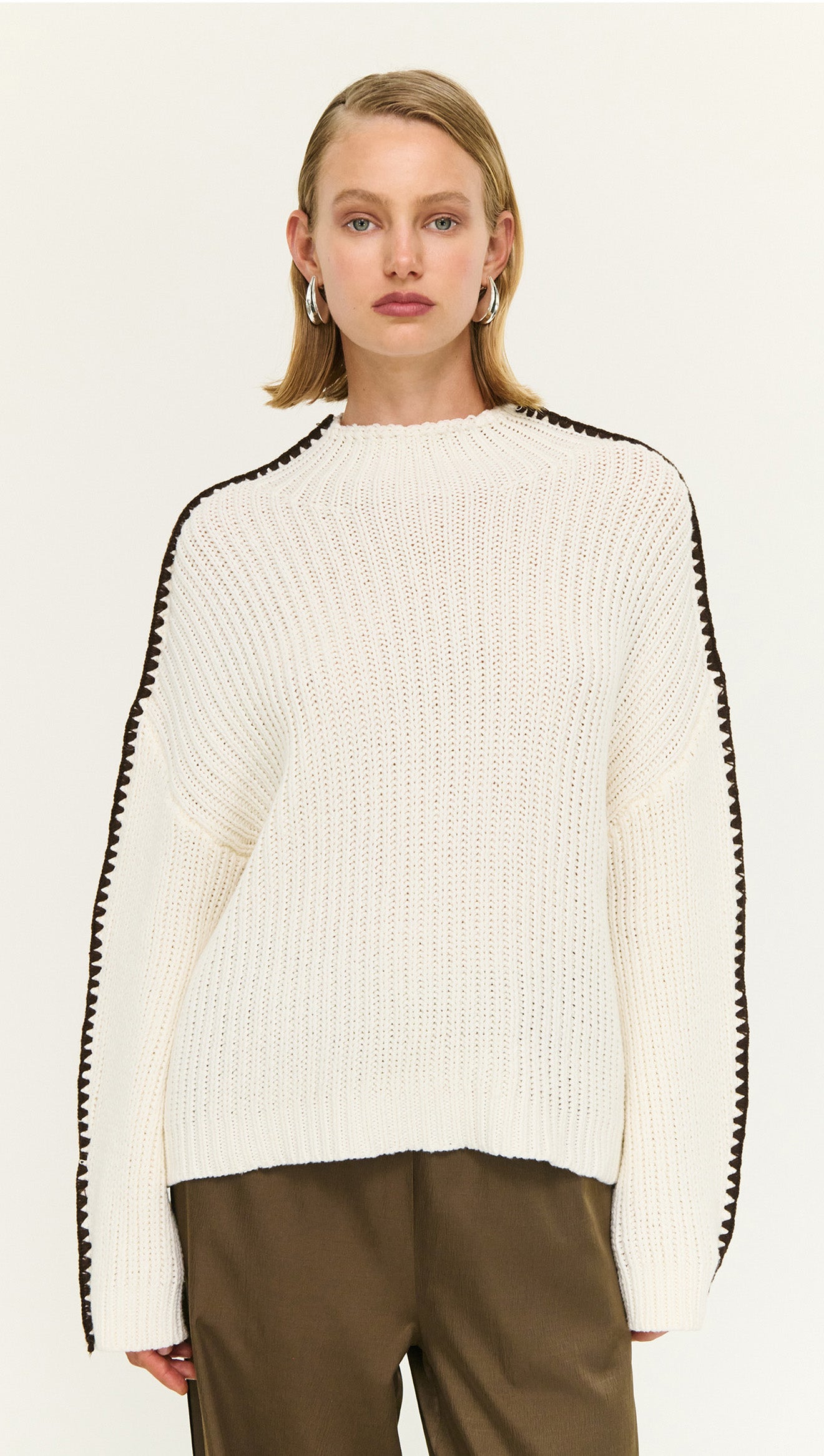 Model wearing a Blanket Stitch Detail High Neck Jumper featuring a relaxed fit and cozy knit in white.