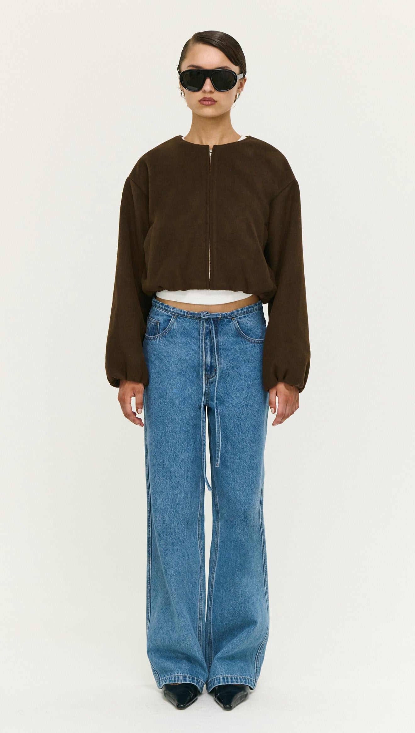 Model wearing a Soft Brushed Cropped Bomber Jacket with oversized jeans and sunglasses, showcasing modern outerwear style.