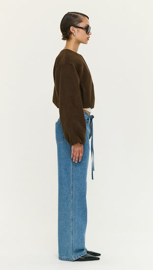 Side view of a model wearing a Soft Brushed Cropped Bomber Jacket paired with high-waisted blue jeans and sunglasses.