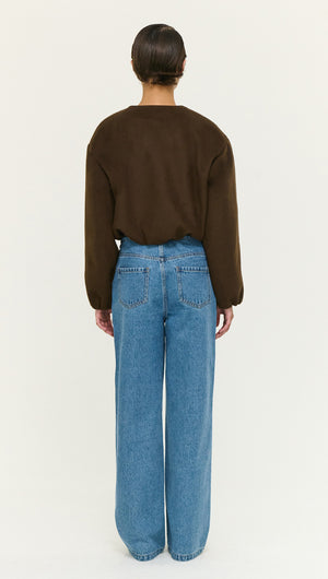 Back view of a model wearing a Soft Brushed Cropped Bomber Jacket, paired with high-waisted blue jeans.